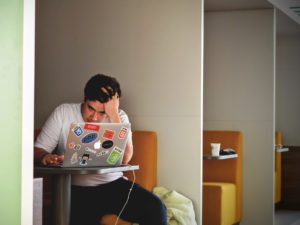 A Stressed man looking at a computer